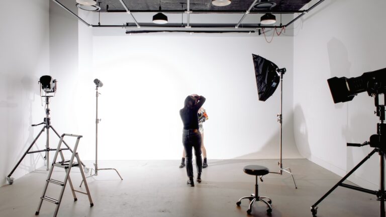 Back view of unrecognizable professional photographer taking photo of anonymous model in modern light studio