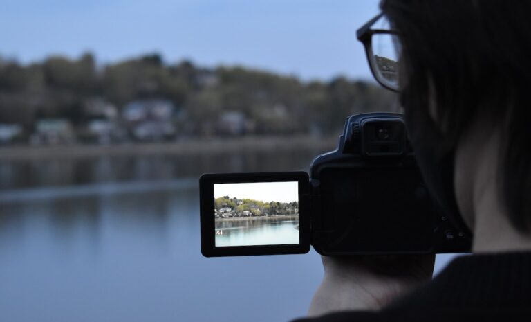 person holding black smartphone taking photo of body of water during daytime